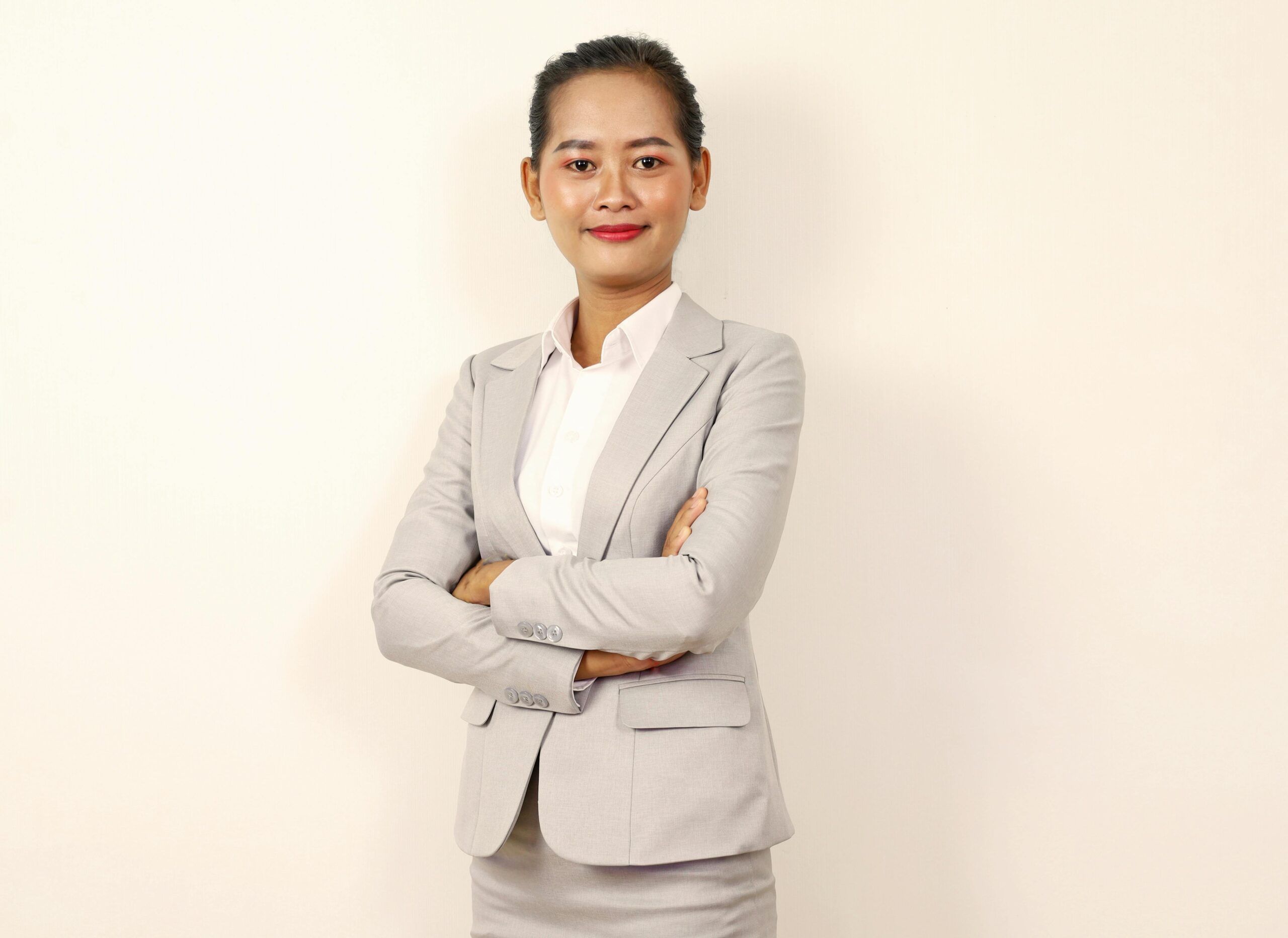 Professional woman in a gray suit with confidence and elegance, standing with crossed arms.