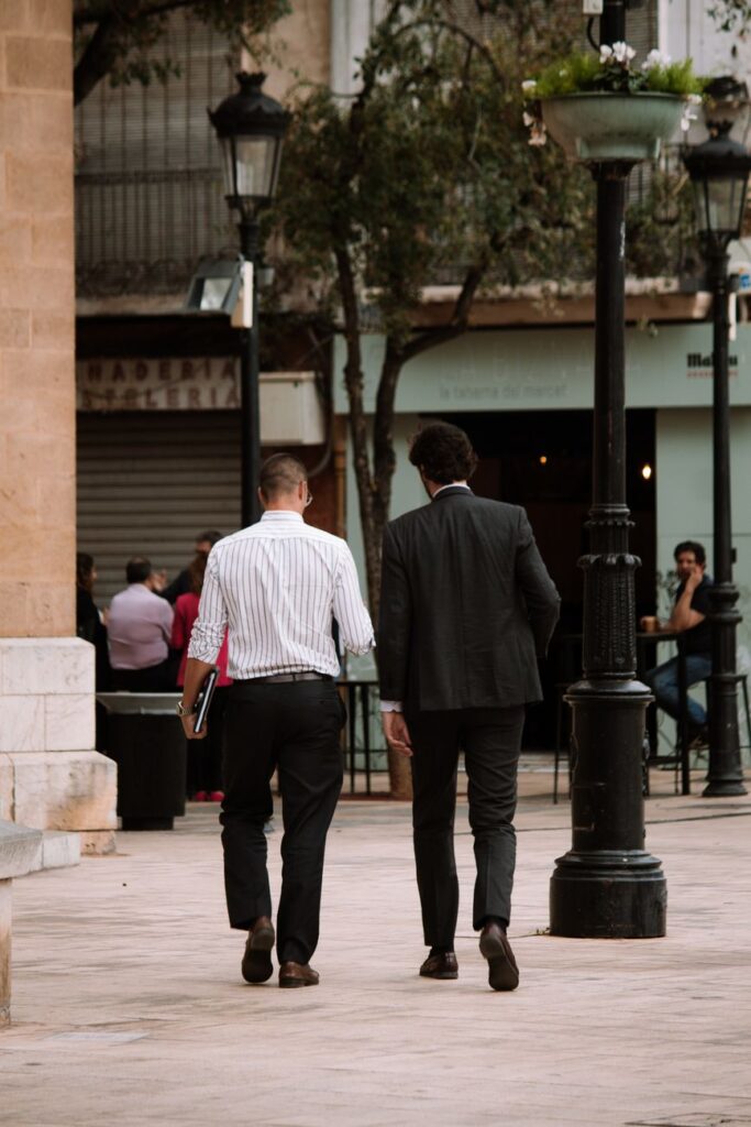 pexels-photo-18969287-18969287 Two men in business attire walking on an urban sidewalk, showcasing city life and street fashion.